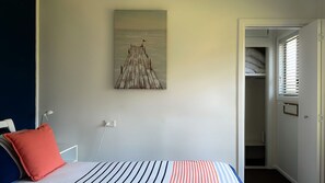 A bedroom with a bed, a painting, and a door leading to a closet.