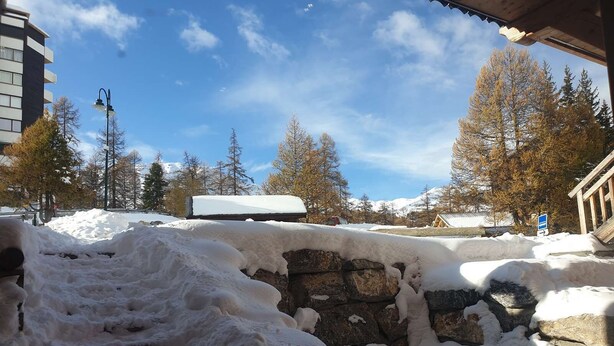 Un'area esterna innevata con un muro in pietra e una struttura in legno.