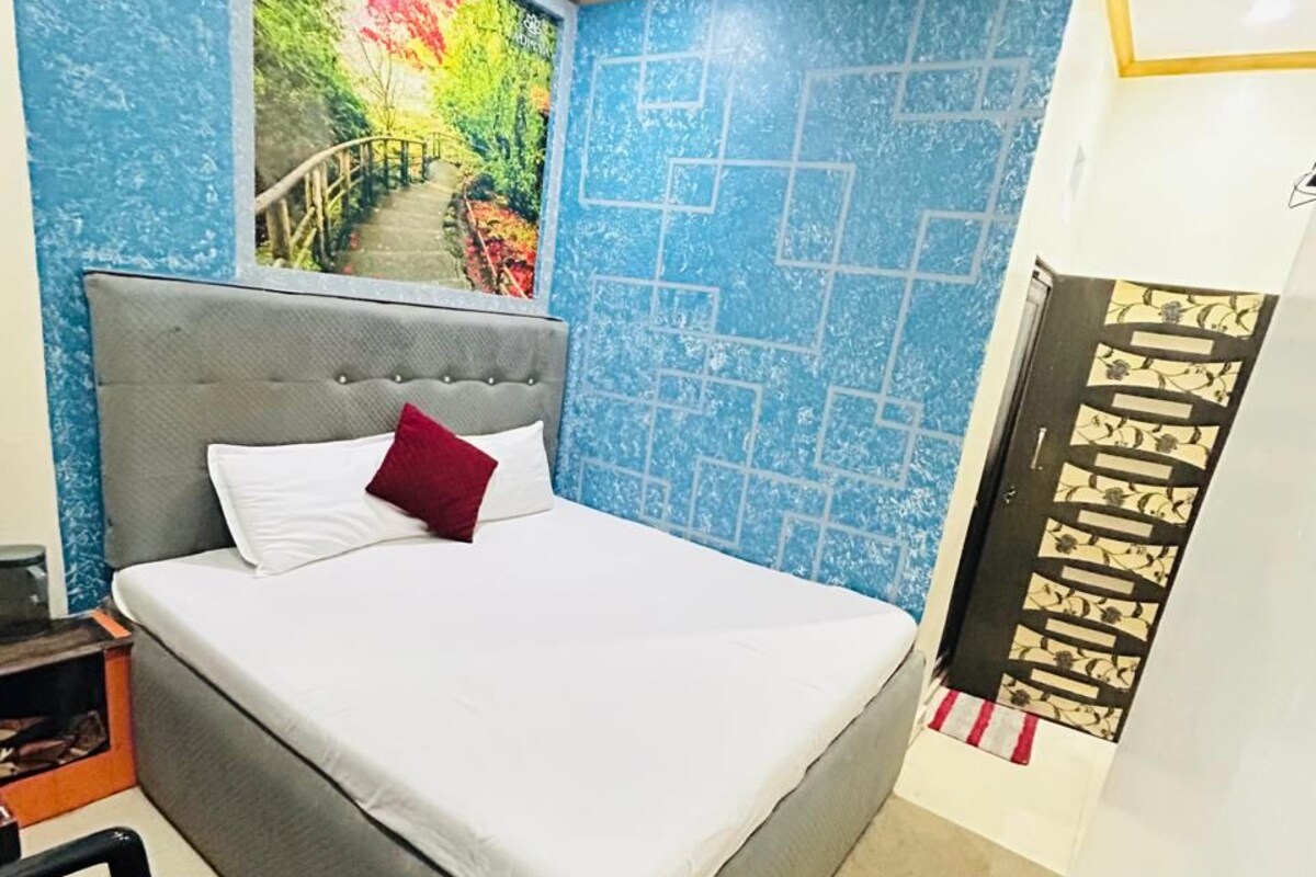 Une chambre à coucher avec un lit, une chaise, un mur orné d’un motif géométrique et un ventilateur de plafond.