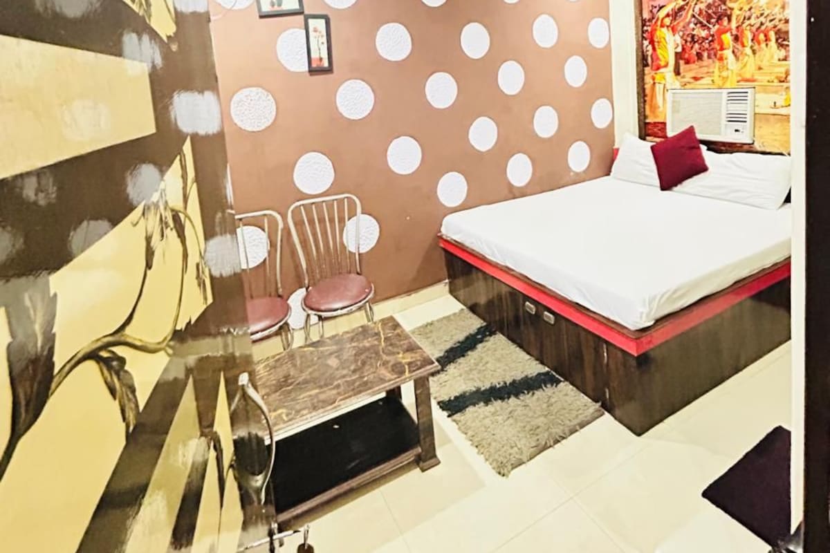 Une chambre à coucher comprenant un lit, une chaise, une petite table, un mur orné de motifs circulaires et un ventilateur de plafond.