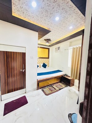 Una habitación de hotel con cama, un armario de madera, un baño con cortina de ducha y suelo de mármol.
