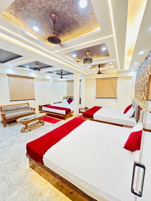 Ein Hotelzimmer mit einem großen Bett, einer Couch, einem kleinen Tisch und einer Decke mit eingelassener Beleuchtung und einem Chandelier.