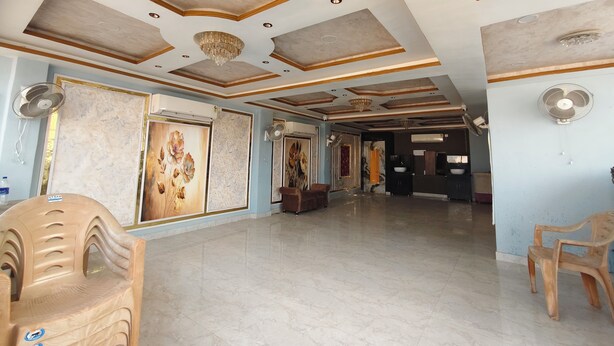 A spacious room with a high ceiling, recessed lighting, and a chandelier. - Hotel Aditya (Varanasi)