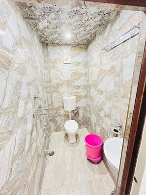 Un bagno con parete in marmo, toilette, bidet, lavabo e zona doccia.