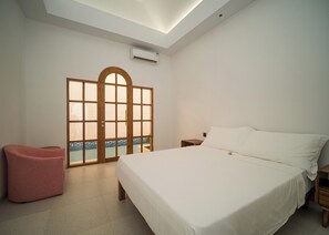 Een slaapkamer met een bed, een roze stoel, een houten deur met uitzicht en een plafondlamp.