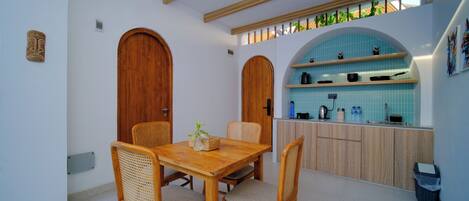 A kitchen with wooden cabinets, a blue tiled backsplash, and a dining area with wicker chairs.