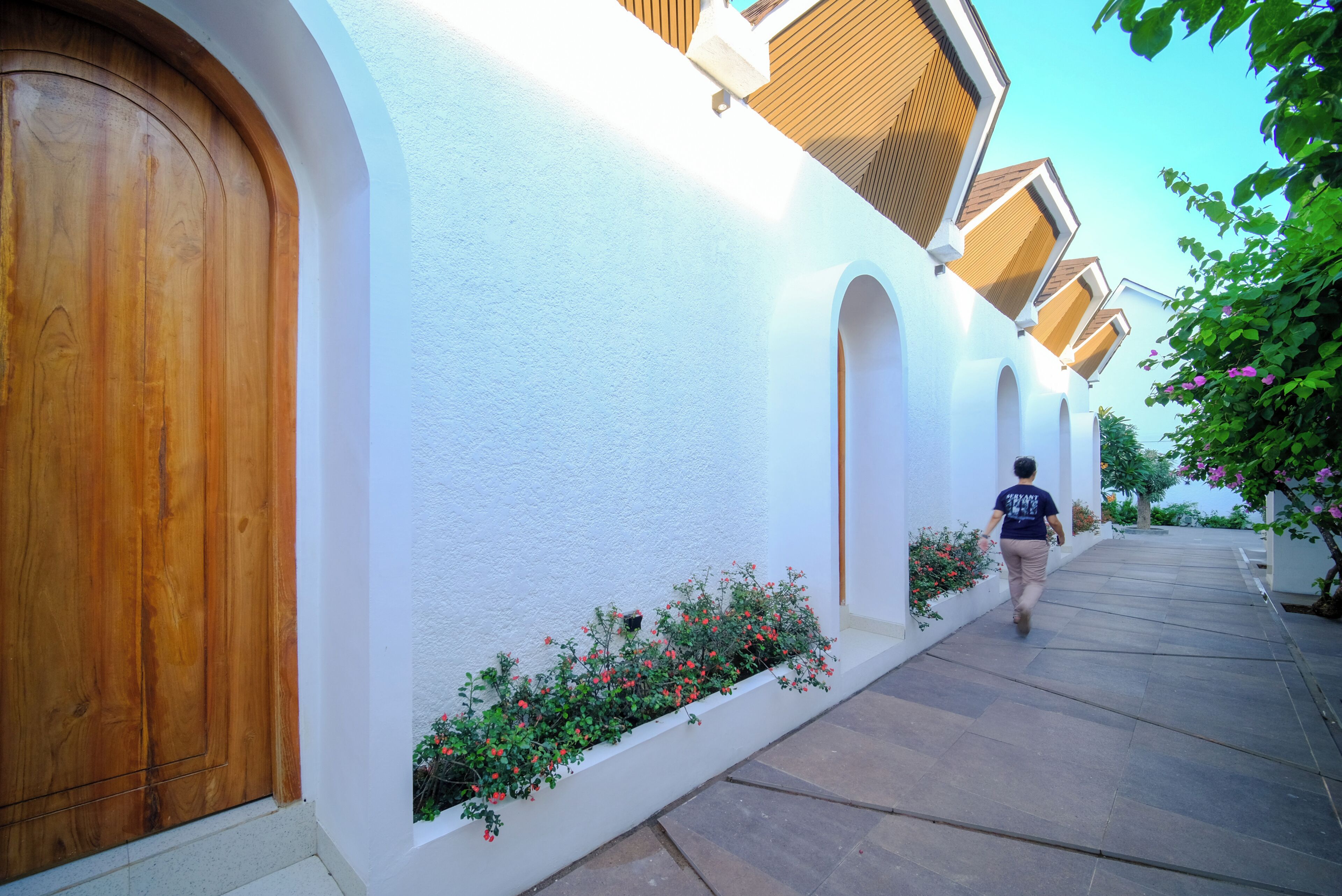 A pathway leading to a building with a wooden door and white walls.