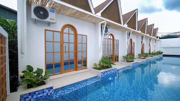 Zona junto a la piscina con piscina enlosada, unidades de aire acondicionado y una fila de ventanas de madera.
