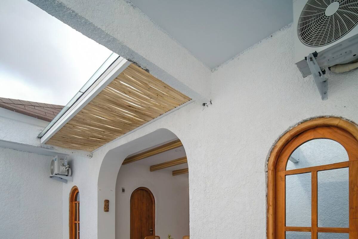 An indoor swimming pool with blue mosaic tiles, wooden doorways, and a ceiling fan.