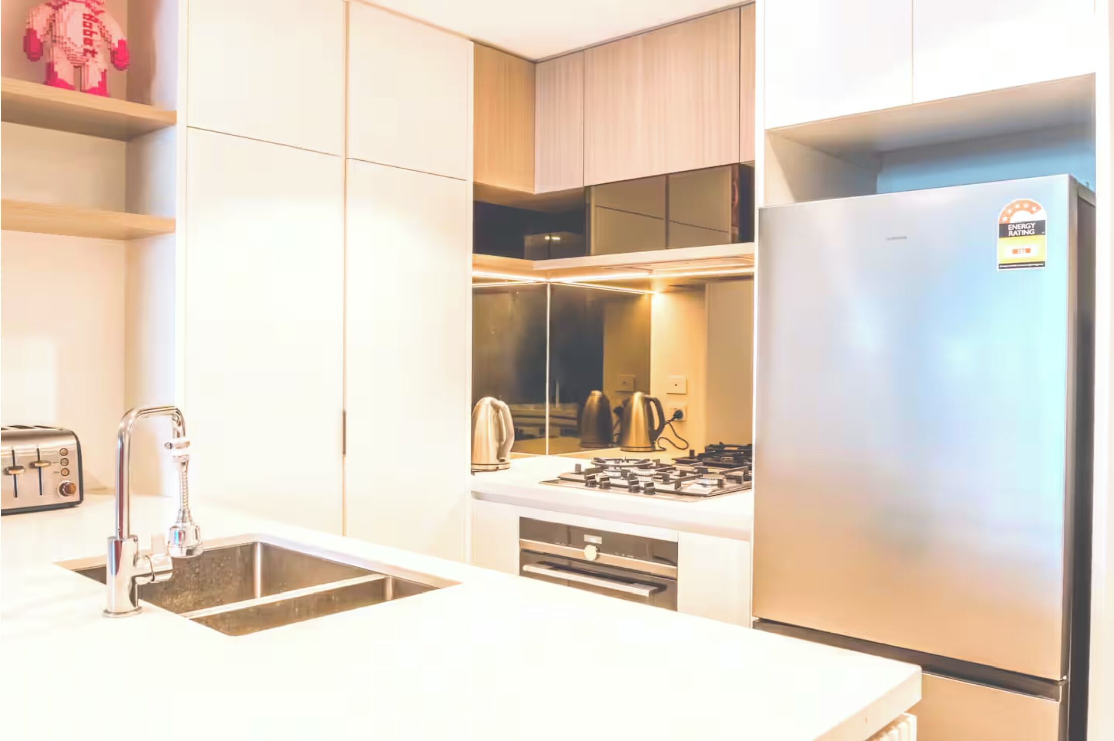 A modern kitchen with a stainless steel refrigerator, a built-in gas stove, and a double sink.