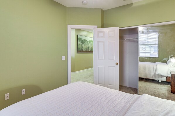 A bedroom with a bed, a door leading to another room, and a window with blinds. - Pool, Patio & Games! Suburban Home in Palmdale (Palmdale)