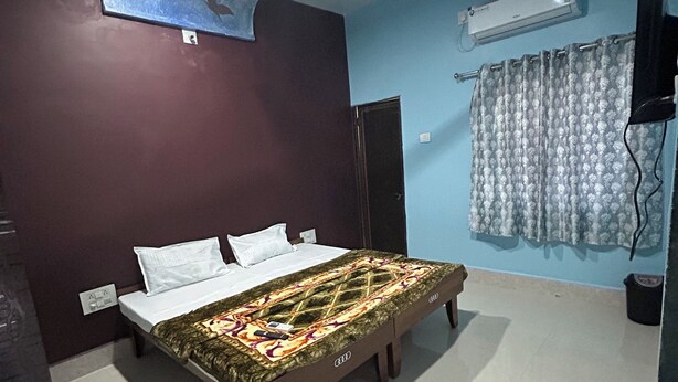A bedroom with a bed, a ceiling fan, an air conditioning unit, and a curtain. - Gaurang home stay
Feel like a home (Dwarka)