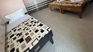 A hotel room with two beds, a wooden bench, and a tiled floor. - Gaurang home stay
Feel like a home (Dwarka)