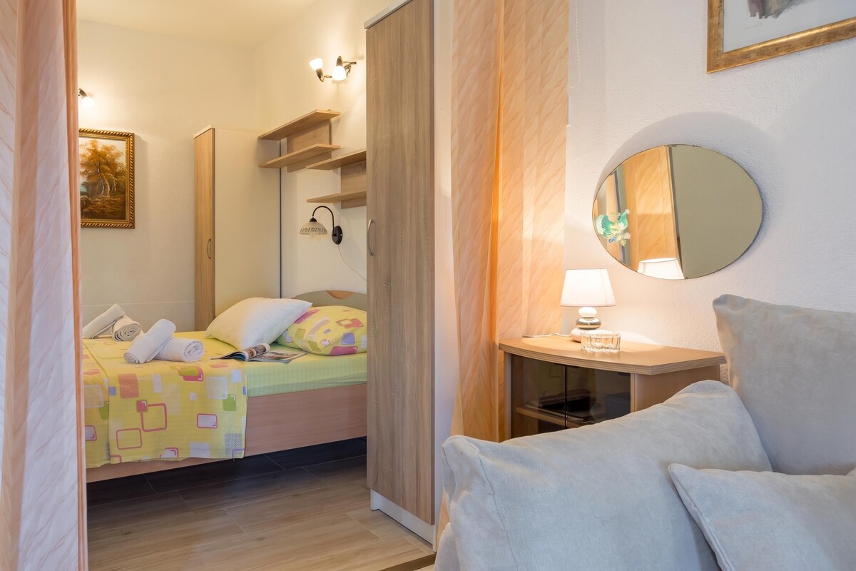 Ett hotellrum med en säng, ett nattduksbord, en lampa, en spegel och en tavla på väggen.