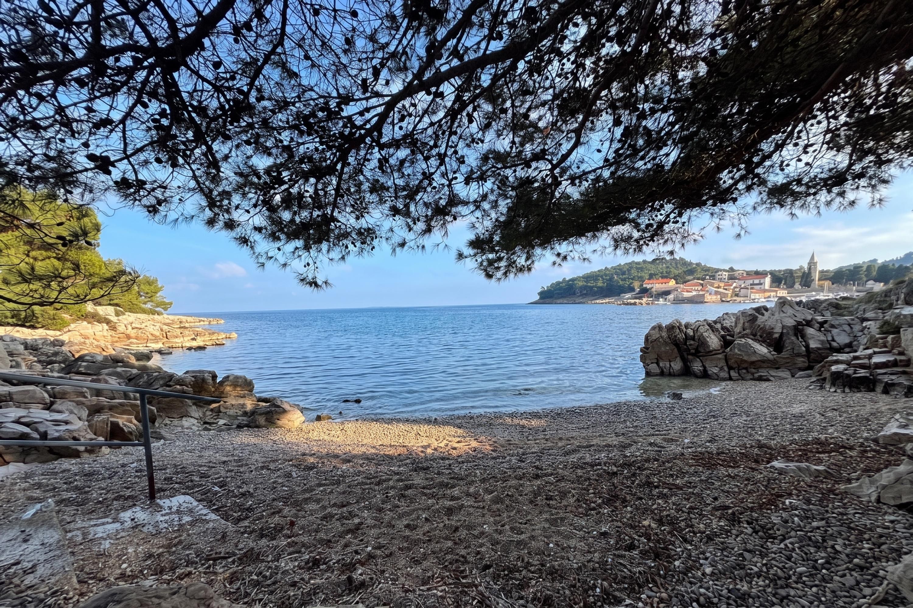 Un paysage côtier caractérisé par un terrain rocheux, une plage de galets et une vue dégagée sur la mer.