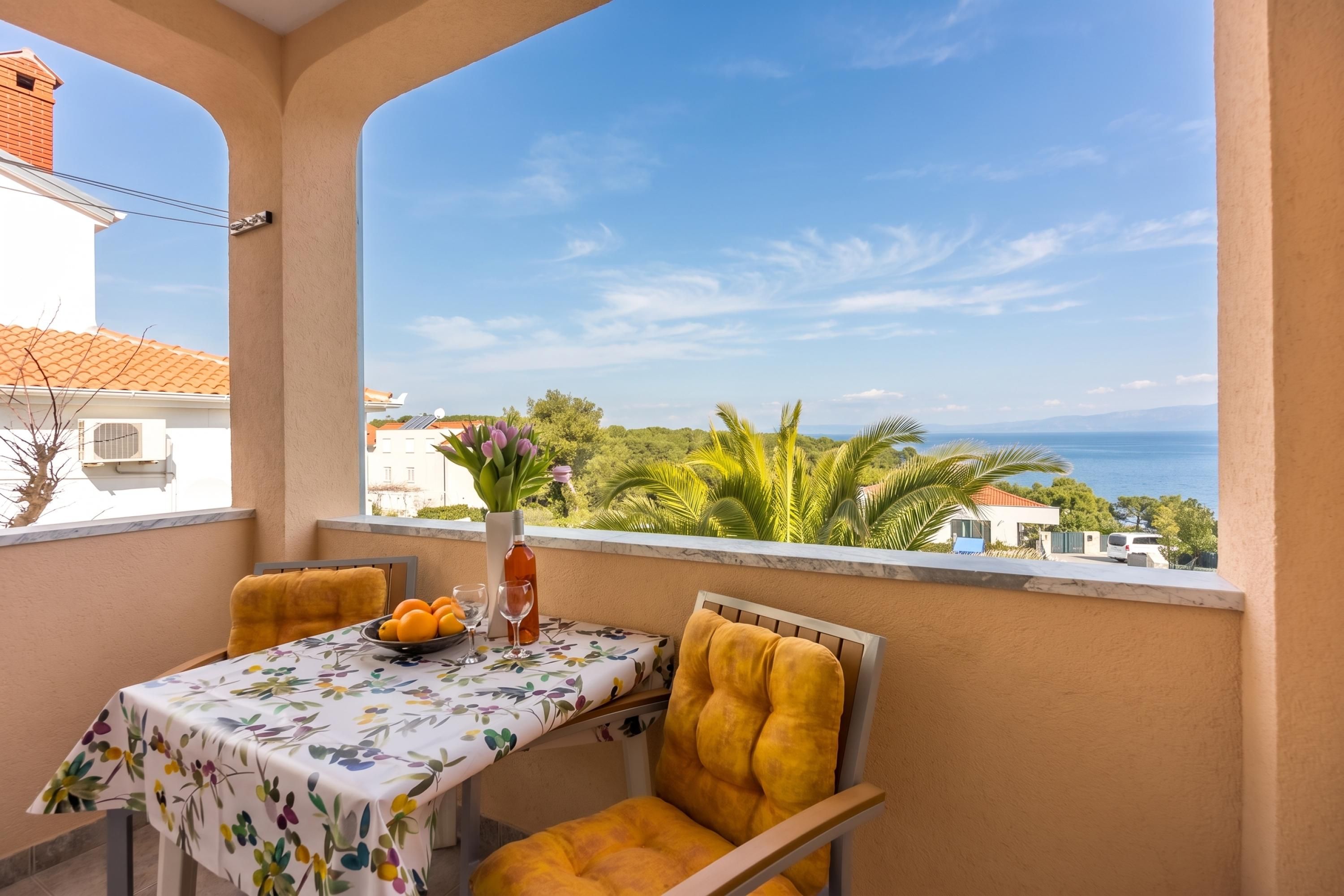 Ein Balkon mit Tisch für Zwei, einem Stuhl und Blick aufs Meer.