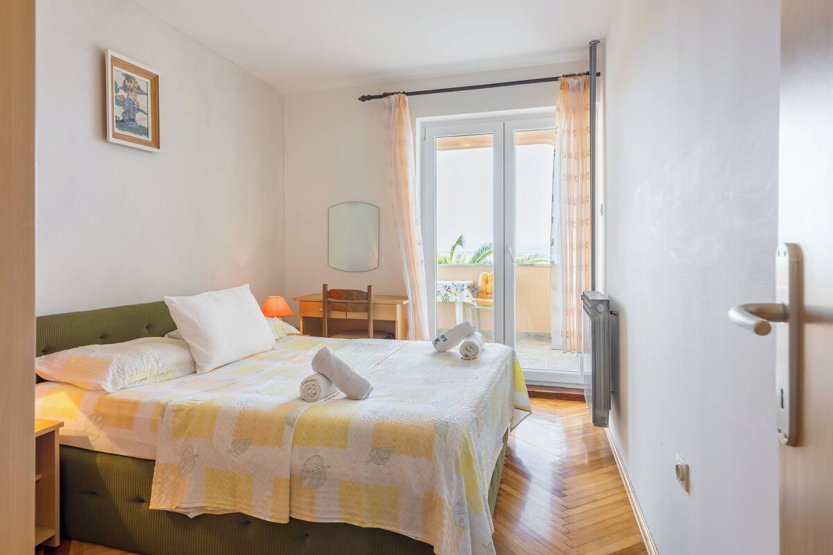 Une chambre à coucher avec un lit, une chaise, une table, une fenêtre et une porte.