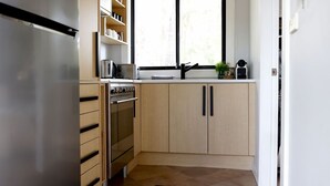 A compact kitchen with a built-in oven, a coffee maker, and a window above the sink. - The Getaway is pet friendly (MANYANA)