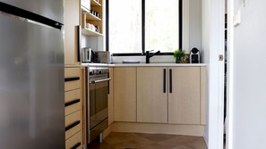A compact kitchen with a built-in oven, a coffee maker, and a window above the sink. - The Getaway is pet friendly (MANYANA)