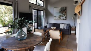 A modern living room with a dark sofa, a round wooden table, and a large window. - The Getaway is pet friendly (MANYANA)