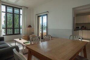 Ein moderner Essbereich mit einem Holztisch und Stühlen, Blick durch eine Glastür und eine Küche mit weißen Schränken.