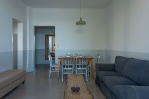 A modern living room with a grey sofa, a wooden coffee table, and a dining area with a table and chairs. - magnificent 2 bedrooms with sea and salt marsh views (Porto-Vecchio)