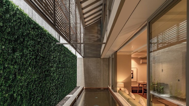 A modern indoor pool with a glass wall on one side and a green hedge on the other. - Brown Feather Pererenan (Pererenan)