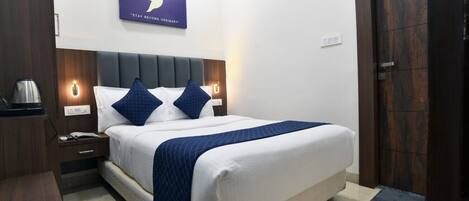 A neatly arranged hotel room with a bed, bedside tables, a coffee maker, and a wall-mounted air conditioner.