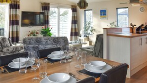 Un coin repas avec une table en bois, dressée pour quatre personnes, entourée de chaises.