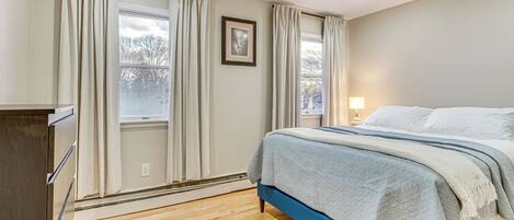Een slaapkamer met een bed, een kaptafel en een raam met gordijnen.