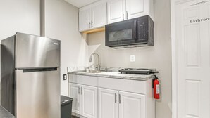 Una cocina con armarios blancos, un refrigerador de acero inoxidable, un microondas y un lavaplatos.
