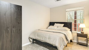 Un dormitorio con cama, mesita de noche, lámpara y armario.
