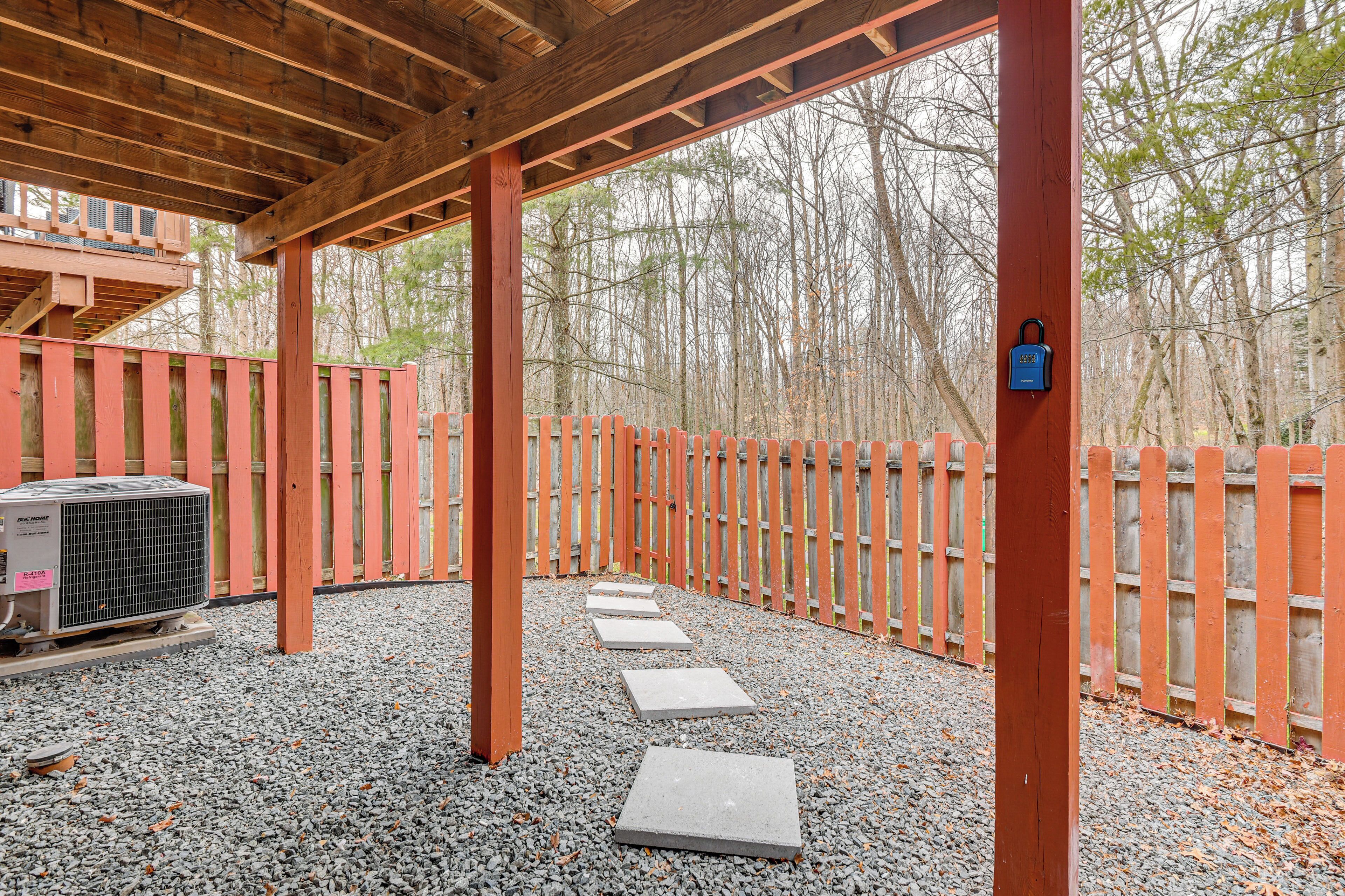 A covered outdoor area with a wooden deck, a red fence, and a gravel path.