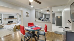 Una cocina moderna con armarios blancos, un refrigerador gris y un comedor con mesa y sillas.