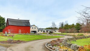 Une grange rouge, une maison et une allée sinueuse bordée de pierres.