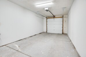 A room with a concrete floor, white walls, and a door with a metal frame.