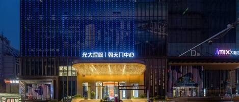 A hotel with a modern facade, illuminated by blue lights, and a prominent entrance with a sign.