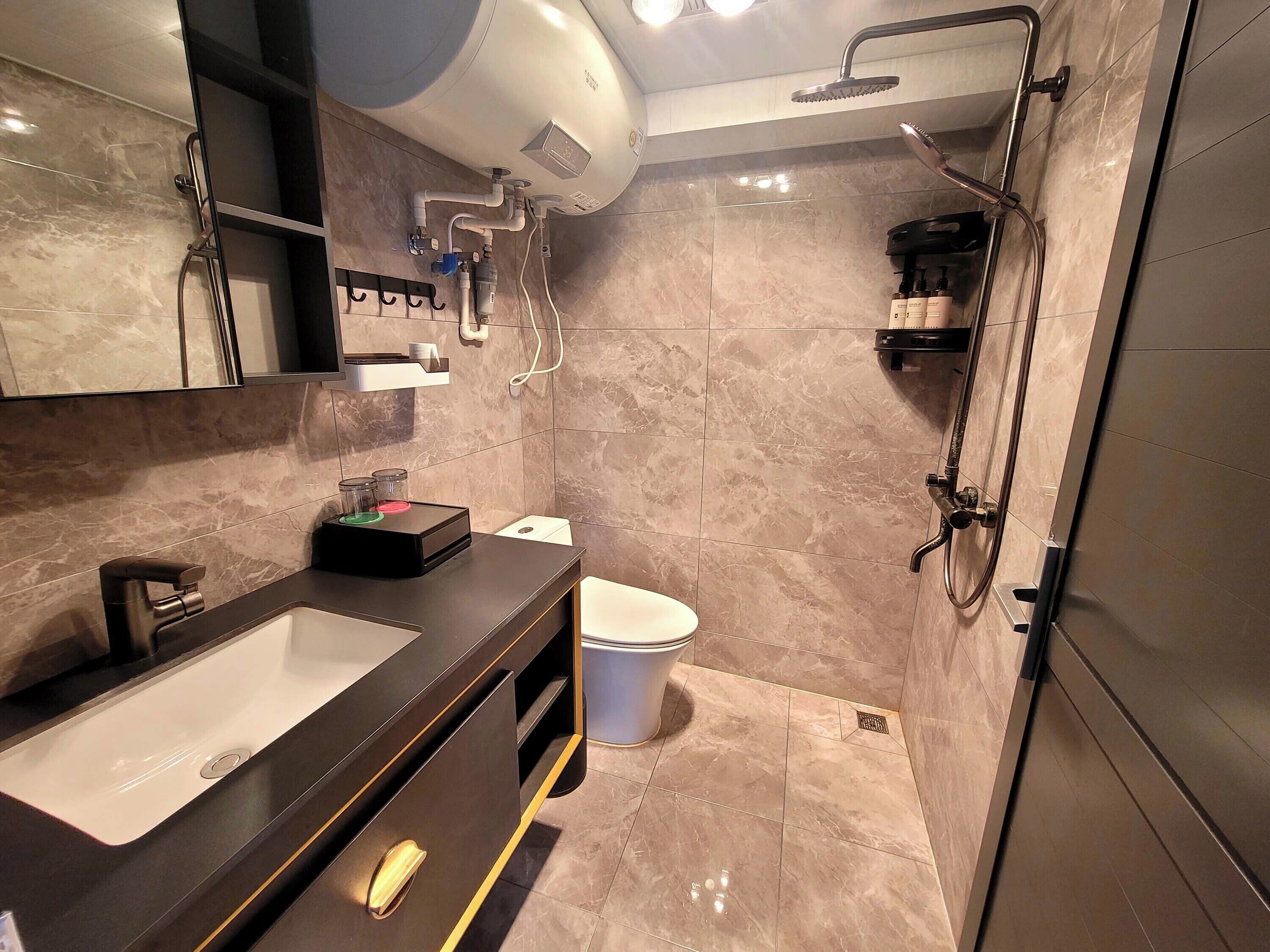 A modern bathroom with a large sink, mirror, and shower.