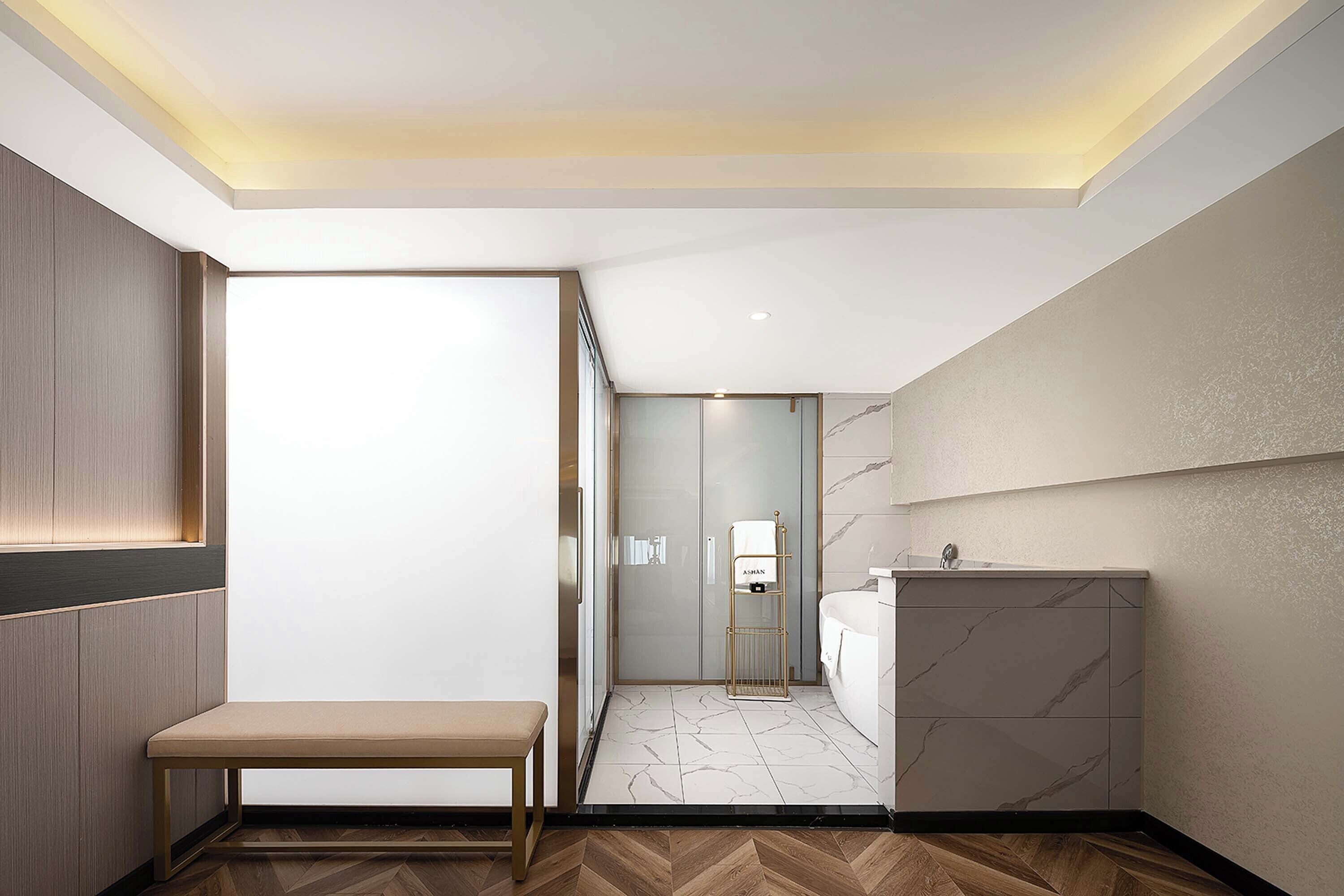 Un baño moderno con piso de mármol, un banco y un lavamanos con encimera de mármol.