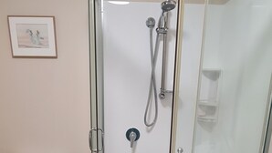 Un baño con ducha de vidrio, inodoro y lavamanos.