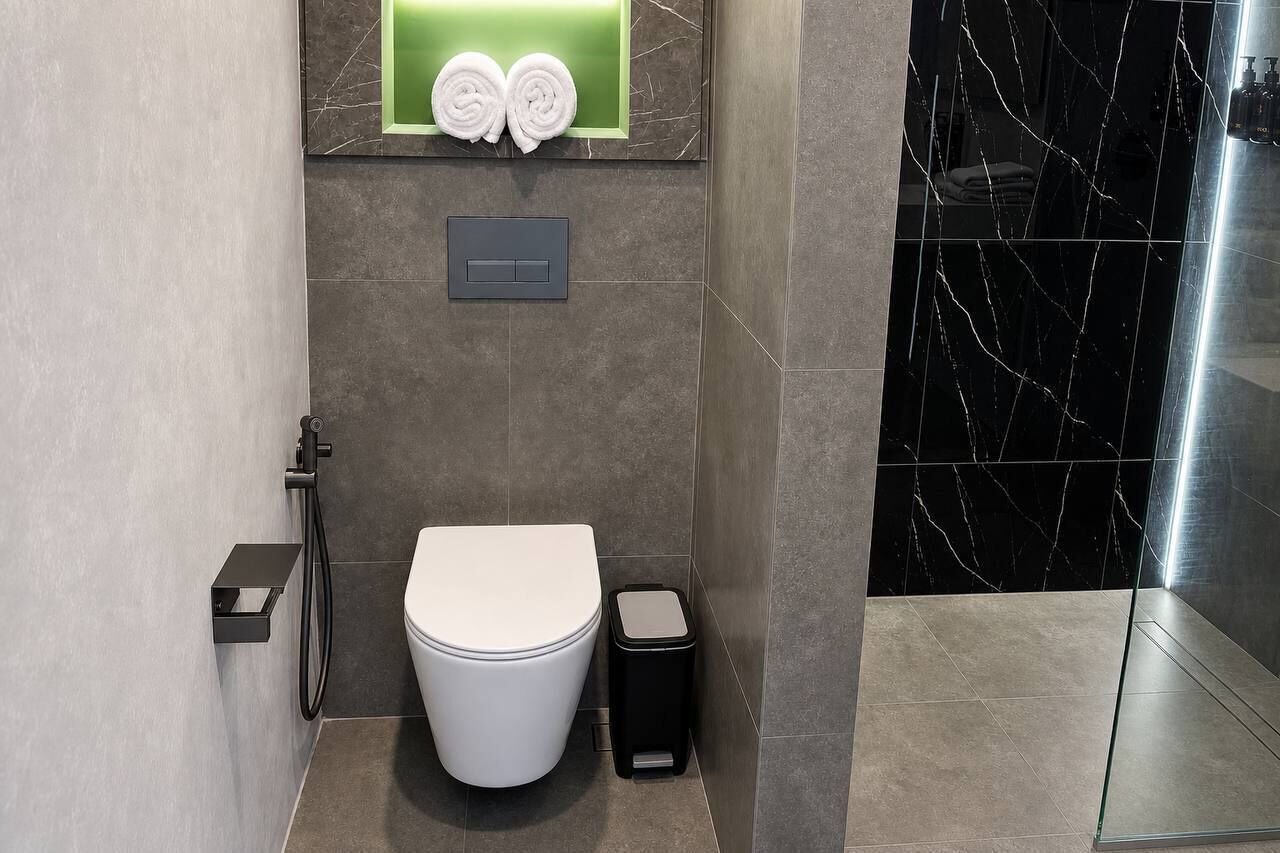 Une salle de bain moderne équipée de toilettes, d’une poubelle et d’un porte-serviettes avec des serviettes.