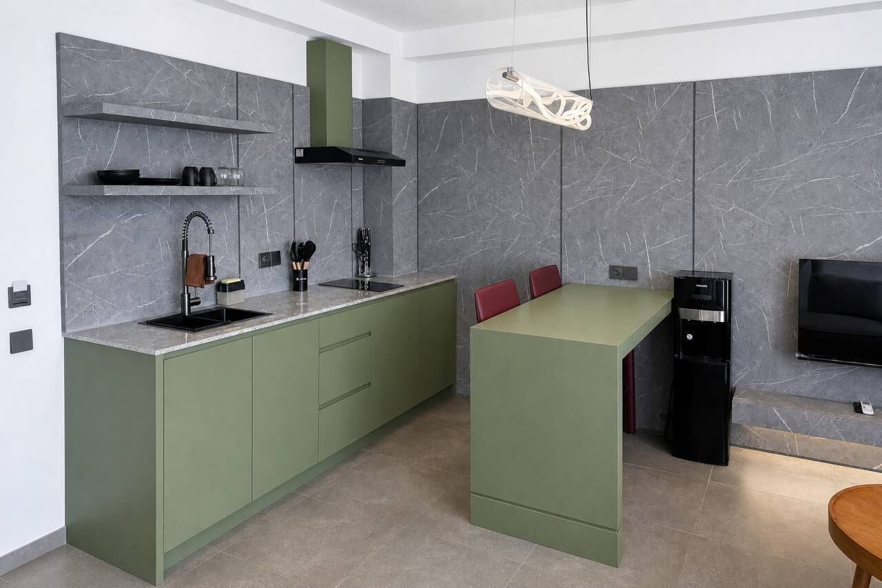A modern kitchen with a built-in island, a black range hood, and a flat-screen TV mounted on the wall.
