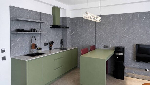 Une cuisine moderne dotée d’un îlot central intégr é, d’une hotte noire et d’un téléviseur à écran plat fixé au mur.