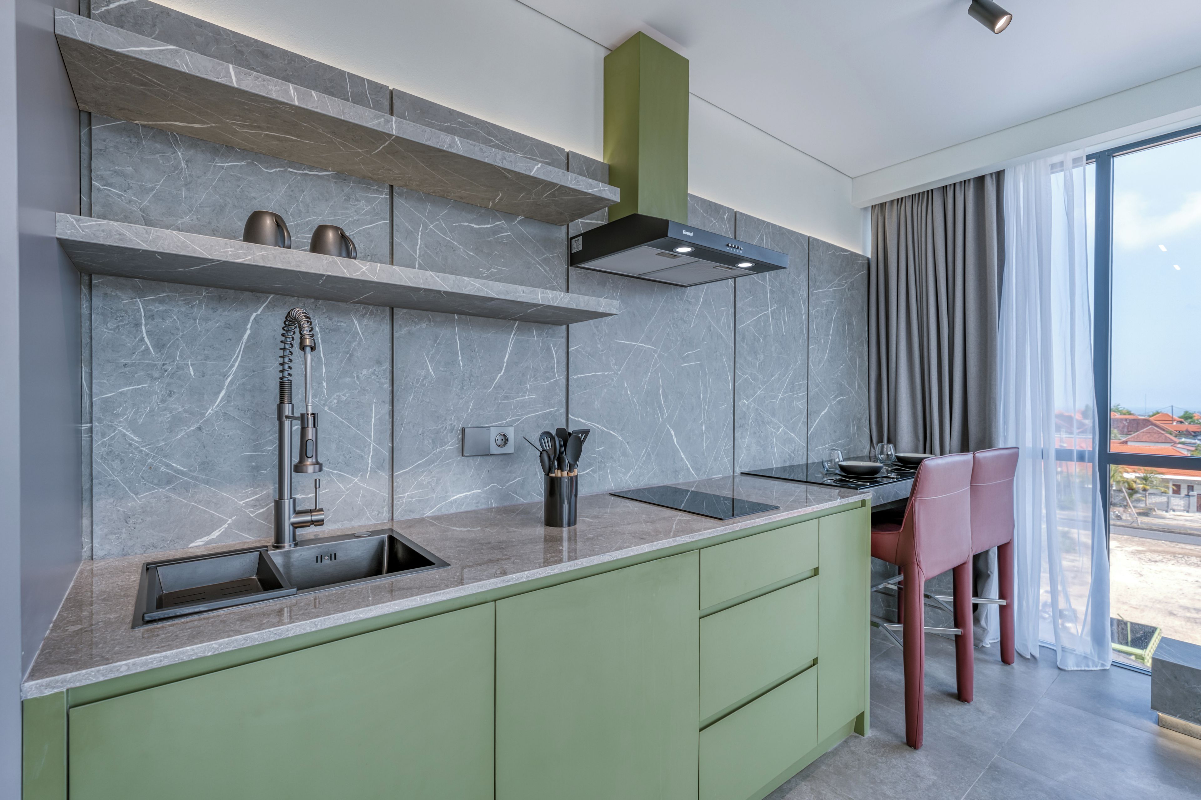 A modern kitchen with a built-in stove, a sink, and a green countertop.