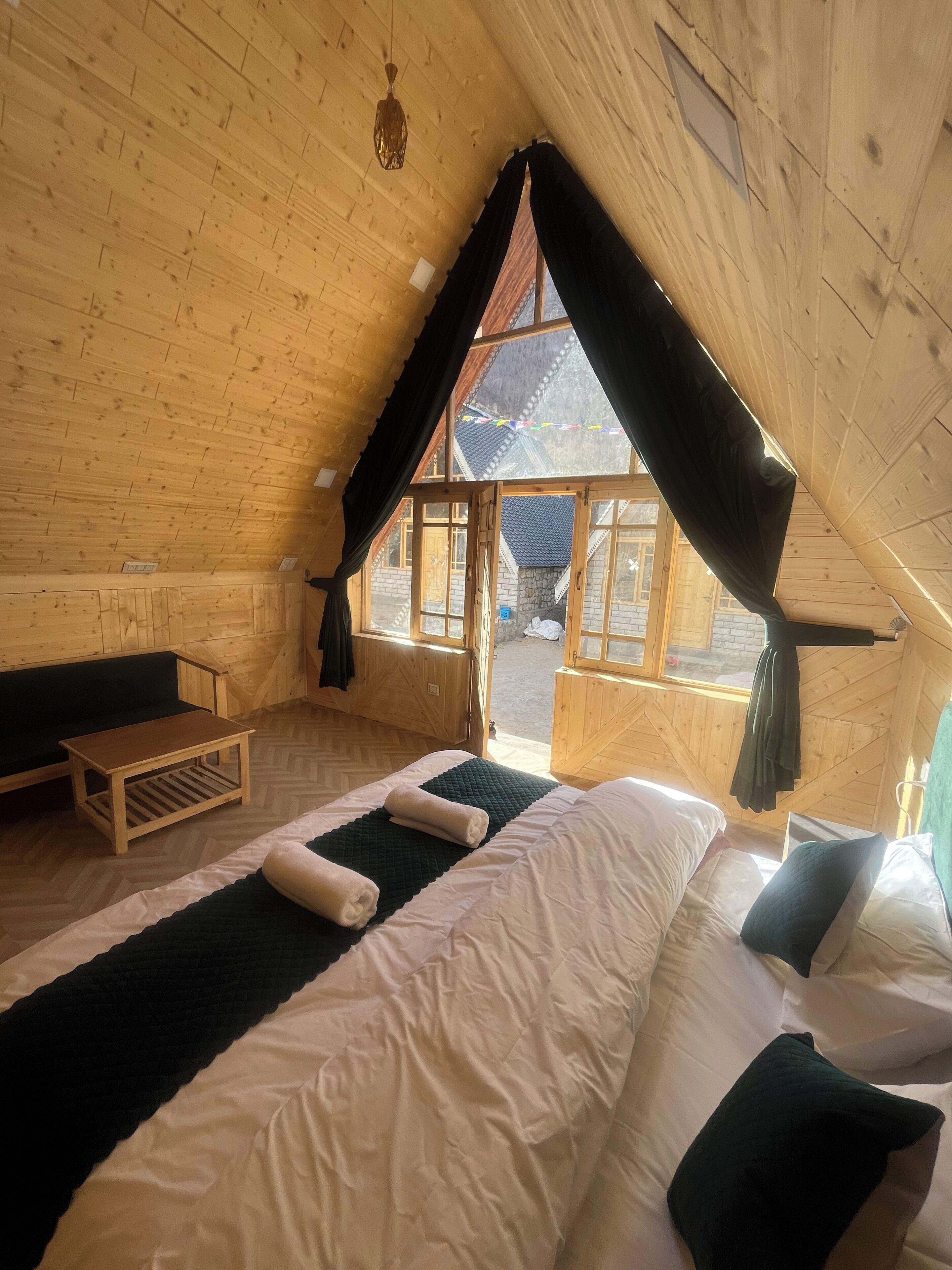 A cozy attic room with a bed, a small table, and a bench.