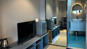 A modern hotel room with a flat-screen TV, a coffee maker, and a mini-fridge. - Puttaya Glow (Pattaya)