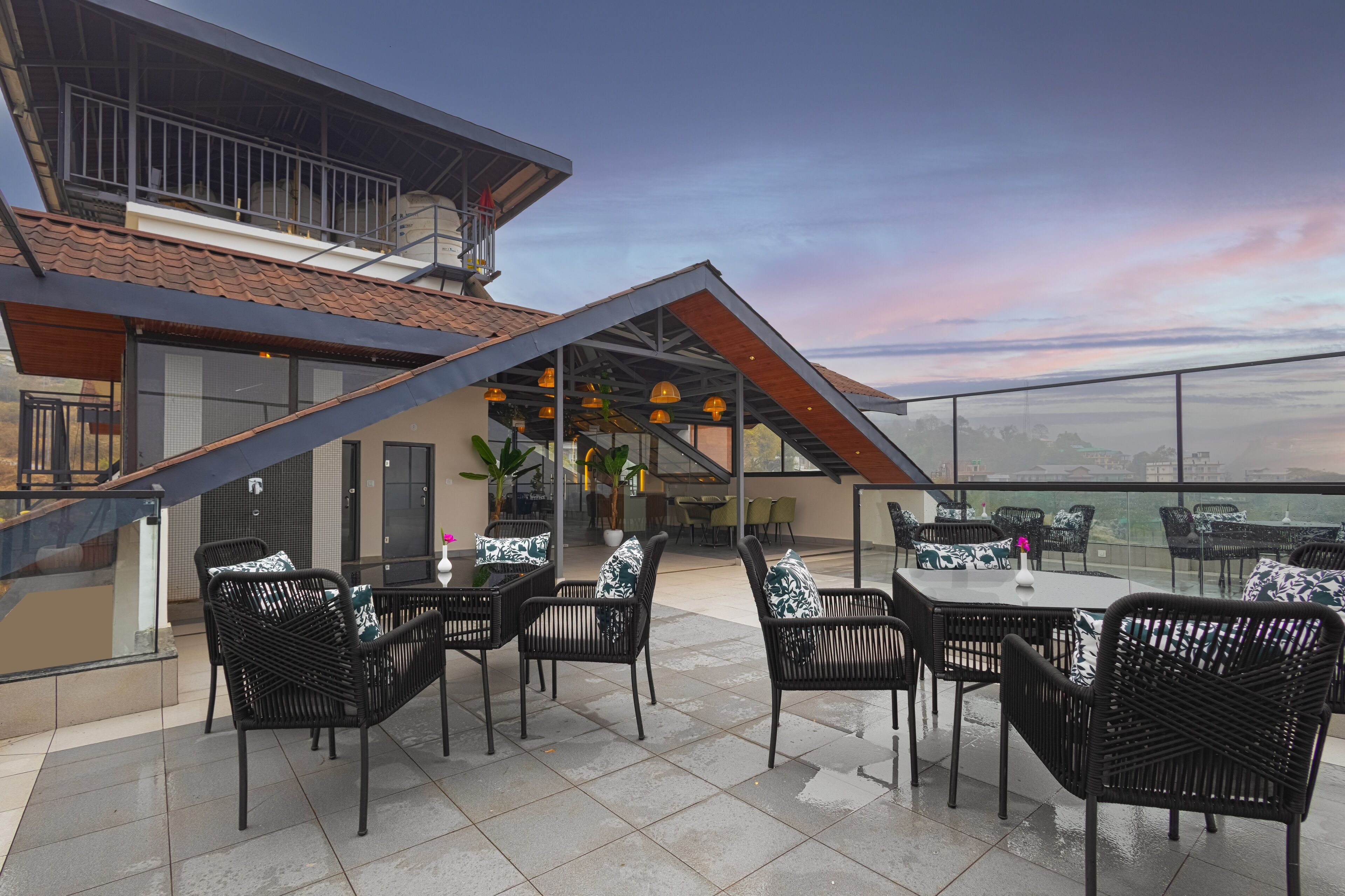 Un patio al aire libre con mobiliario de mimbre negro y barandilla de vidrio.