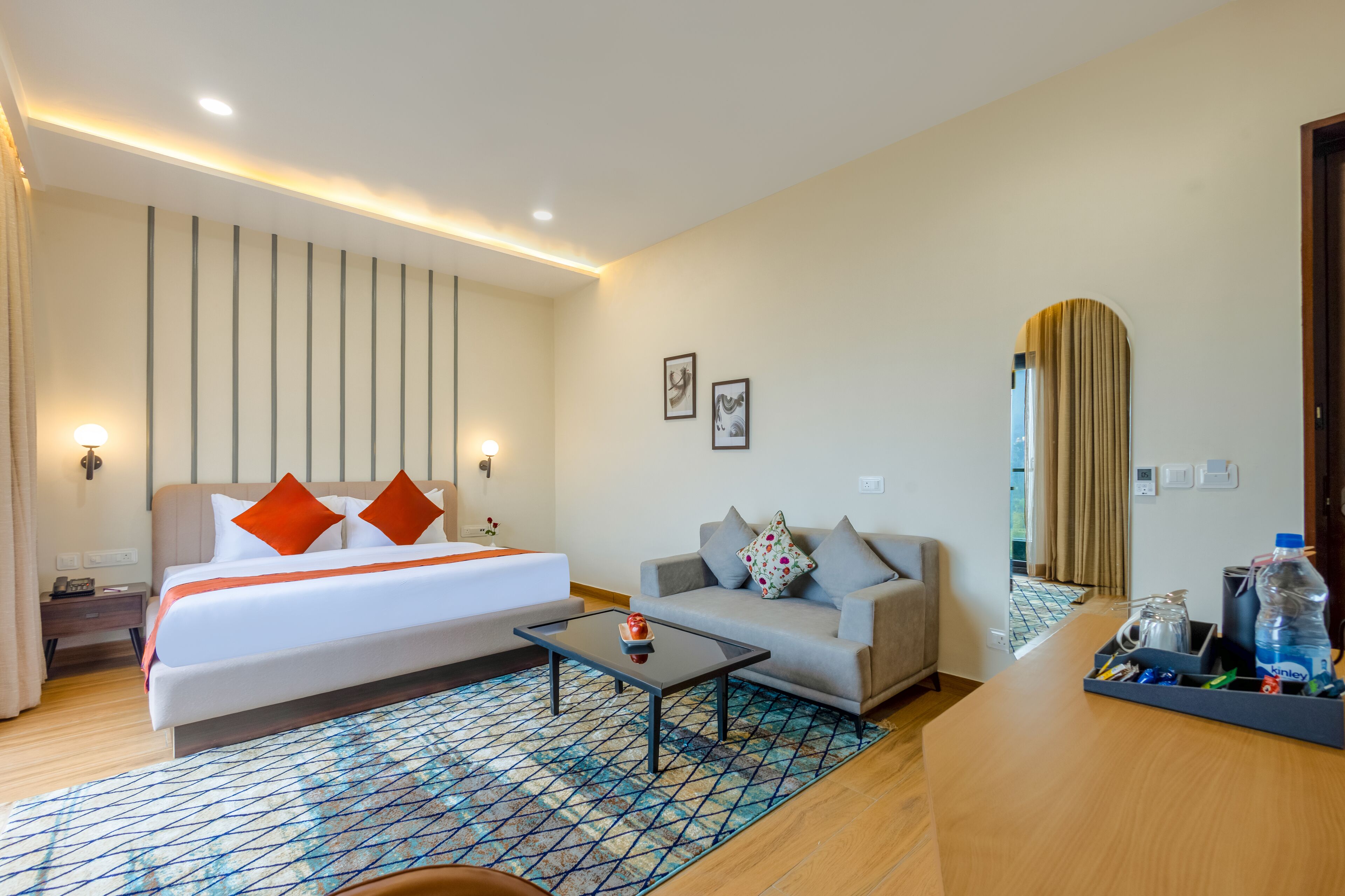 A hotel room with a bed, a sofa, a coffee table, and a desk.