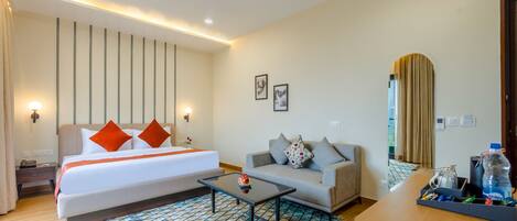 A hotel room with a bed, a sofa, a coffee table, and a desk.