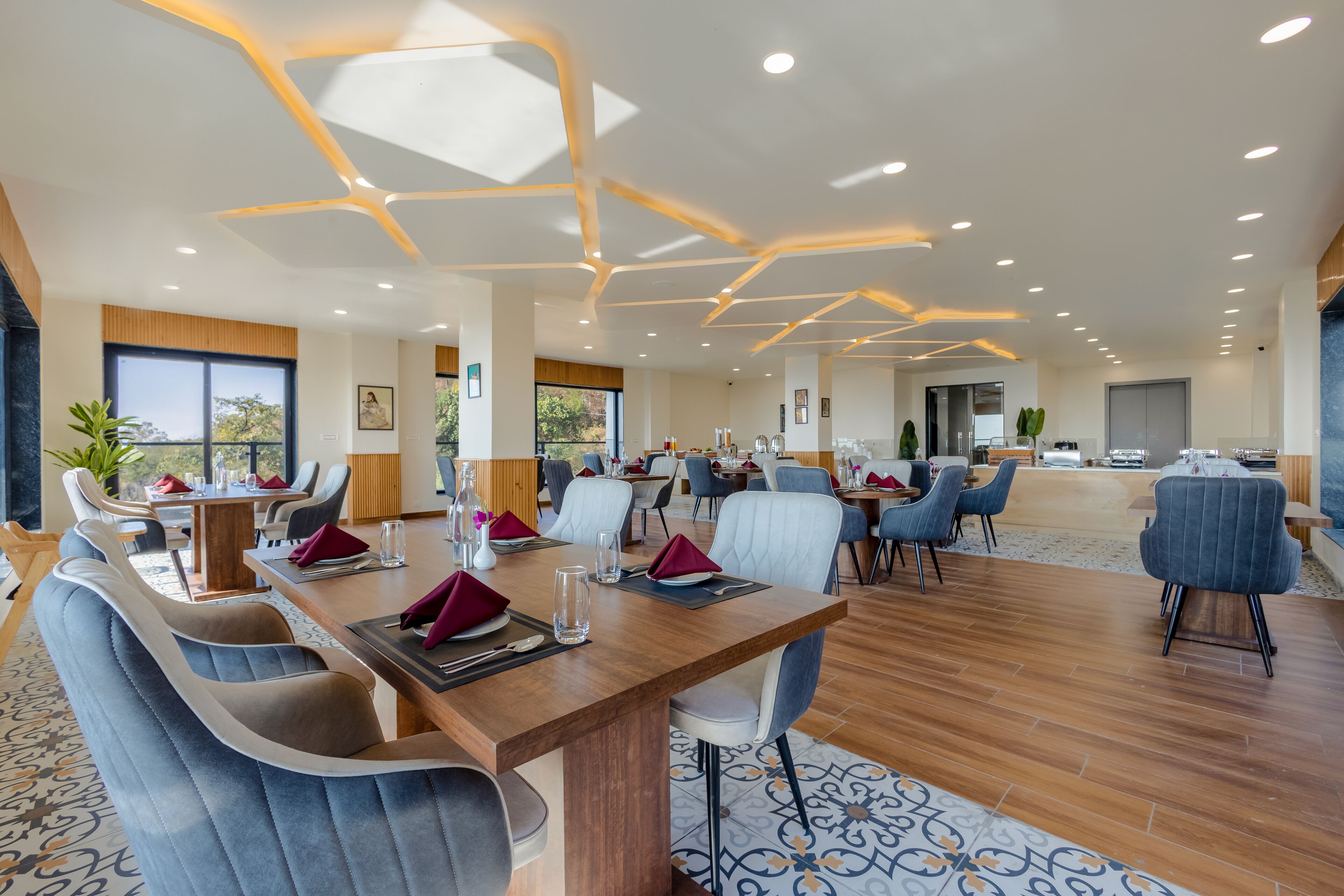A spacious dining area with a long wooden table, multiple chairs, and a modern ceiling design.
